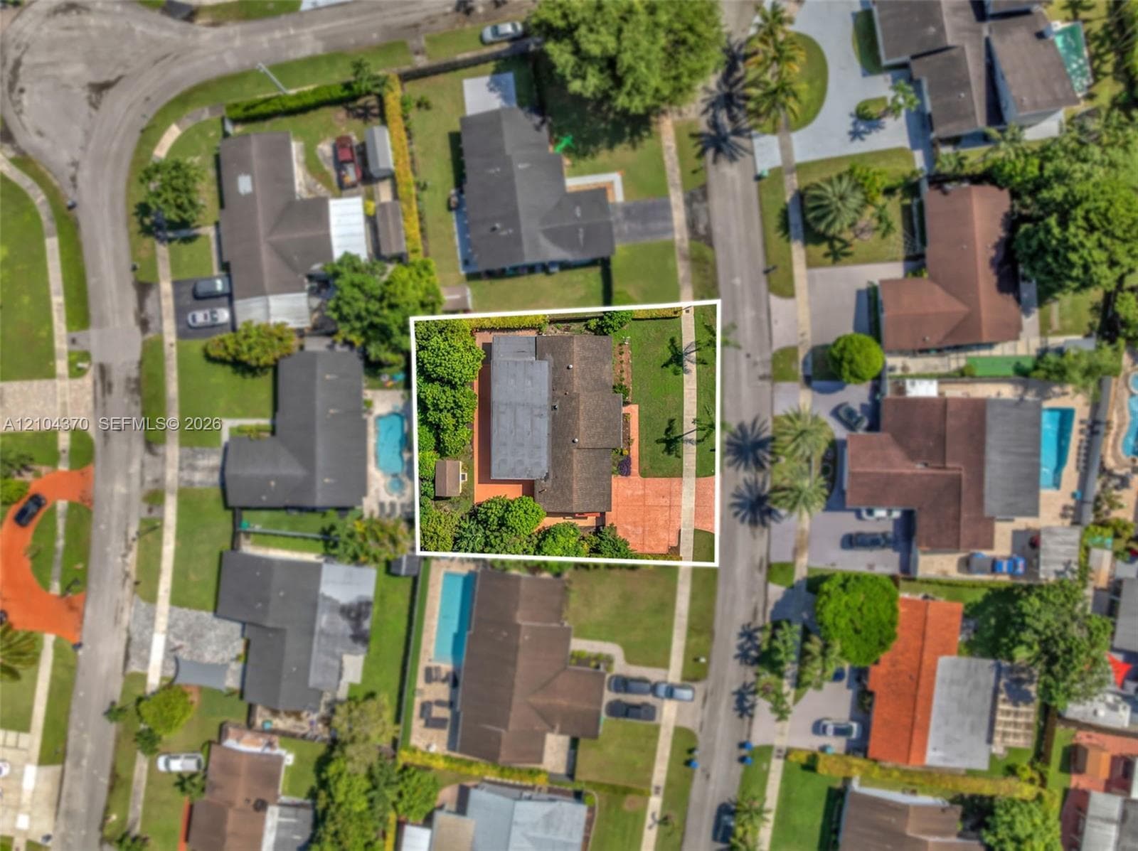 Aerial perspective of a suburban neighborhood featuring low-density residential streets, mature trees, expansive green space, and proximity to regional commercial infrastructure