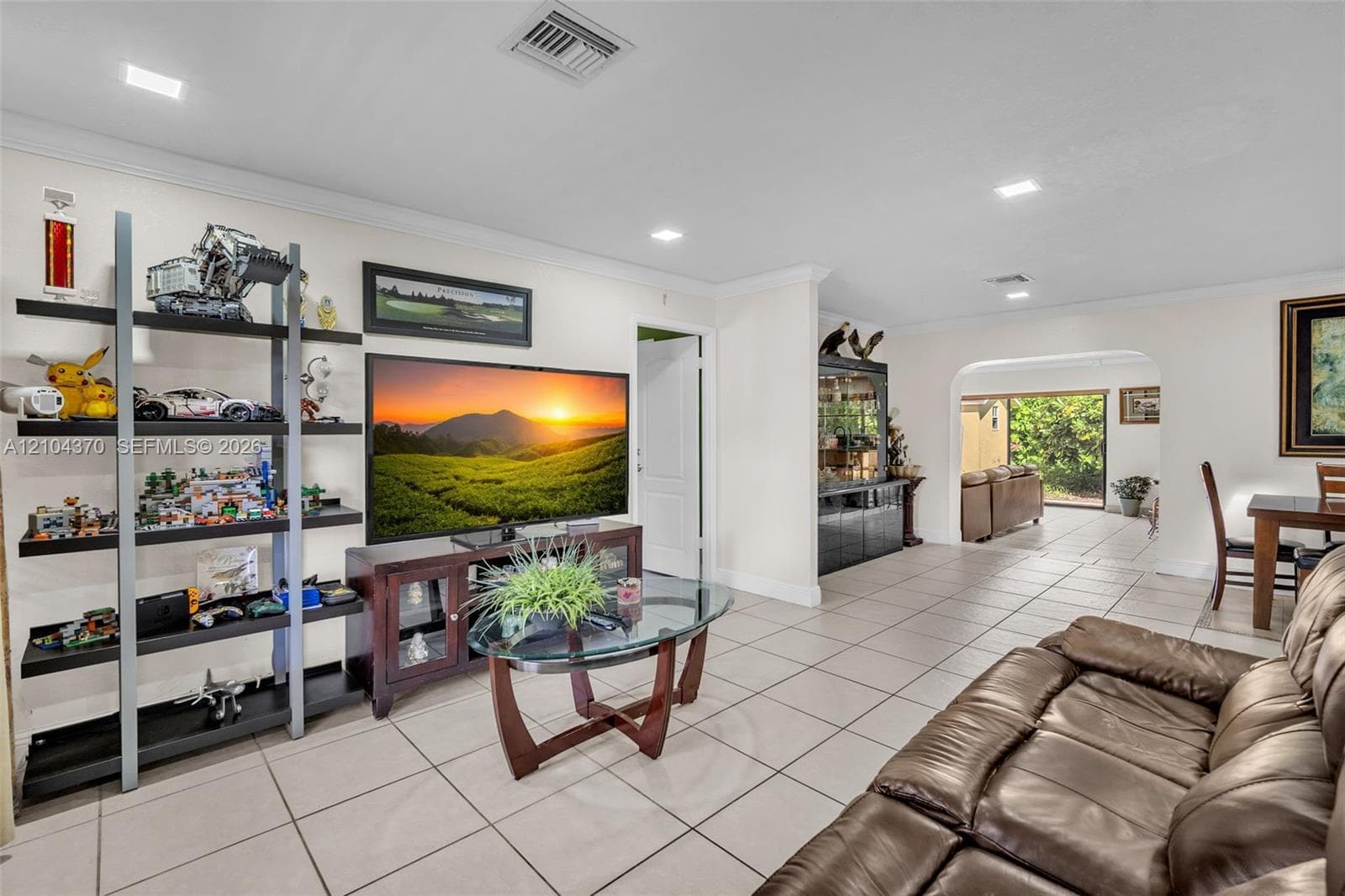 Neutral-toned floor tiles, recessed lighting, crown molding, and a paneled entry door