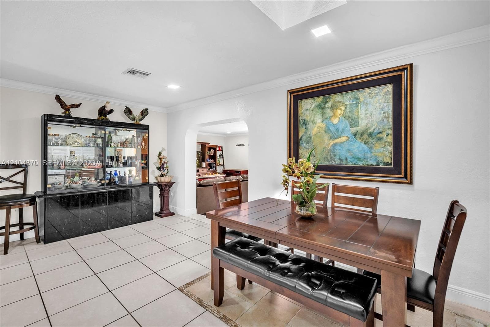 Open-concept interior featuring light-toned tile flooring, recessed lighting, a ceiling skylight, and louvered built-in closet doors