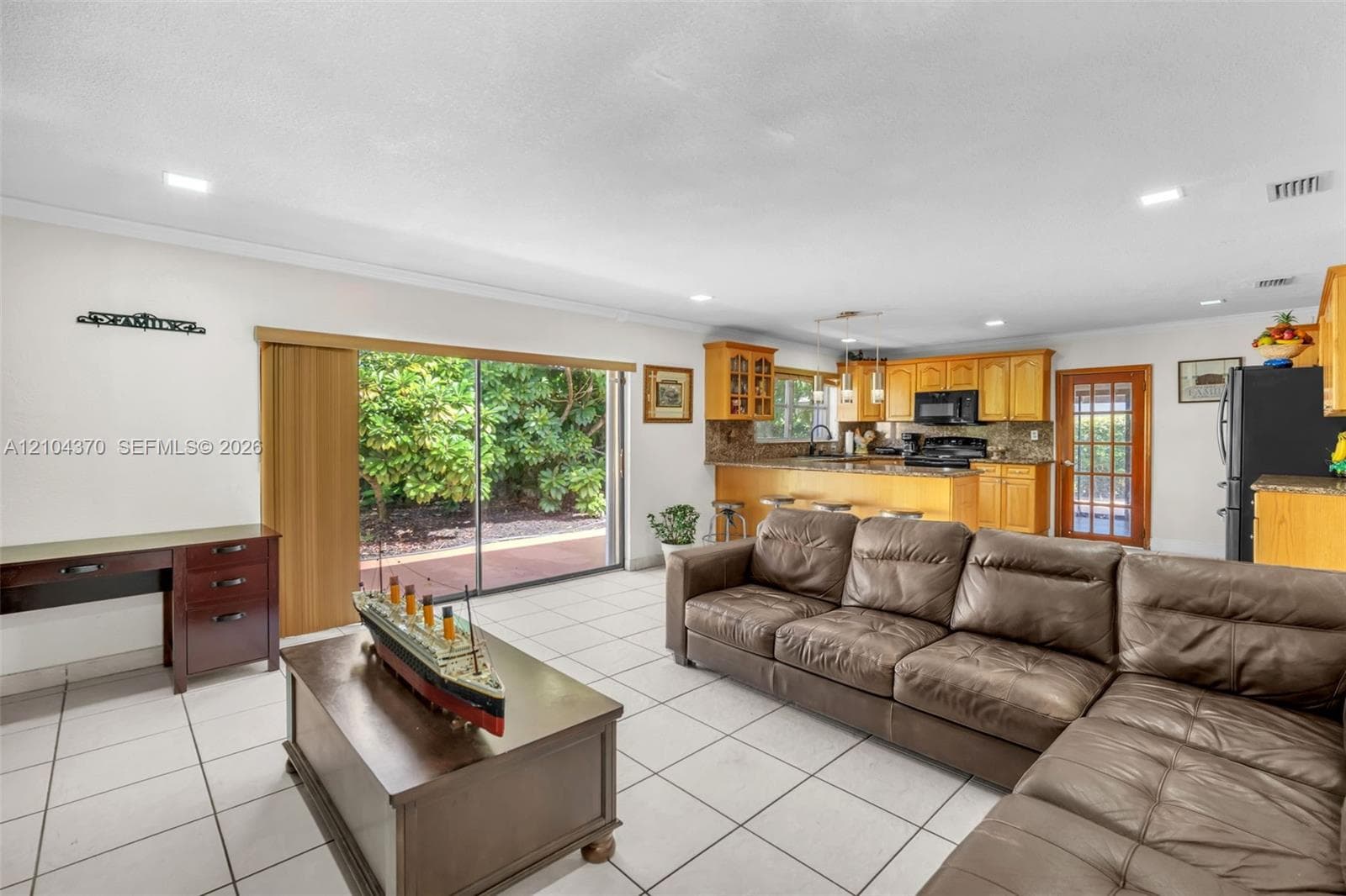 Large-format tile flooring, recessed lighting, crown molding, arched room entry, and built-in wood cabinetry