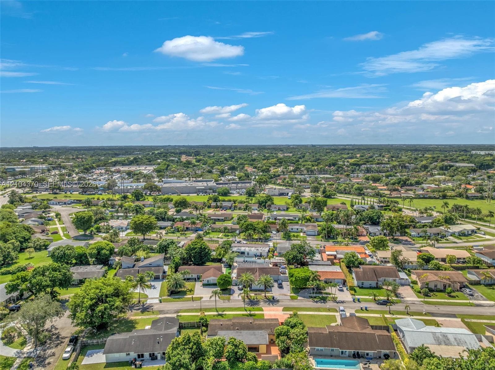 Aerial perspective of a residential neighborhood featuring mature palm trees, paved streets, maintained lawns, and low-density housing clusters