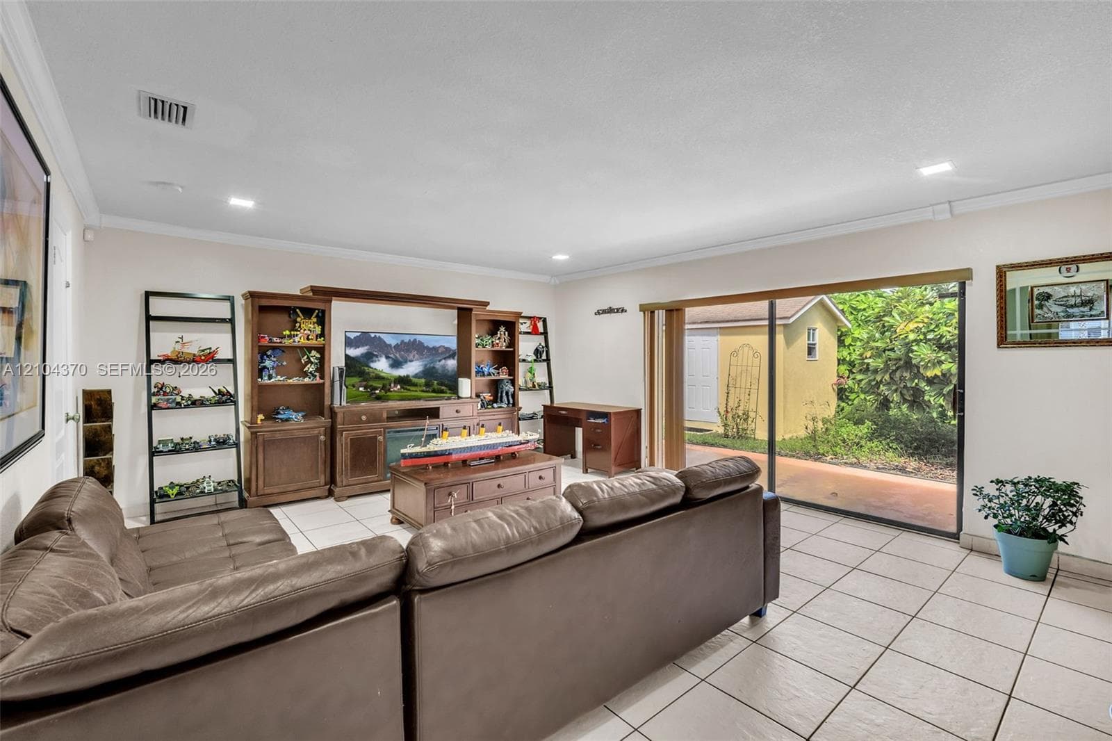 Open-concept interior featuring light-toned tile flooring, recessed ceiling lighting, a curved architectural archway, and white louvered closet doors