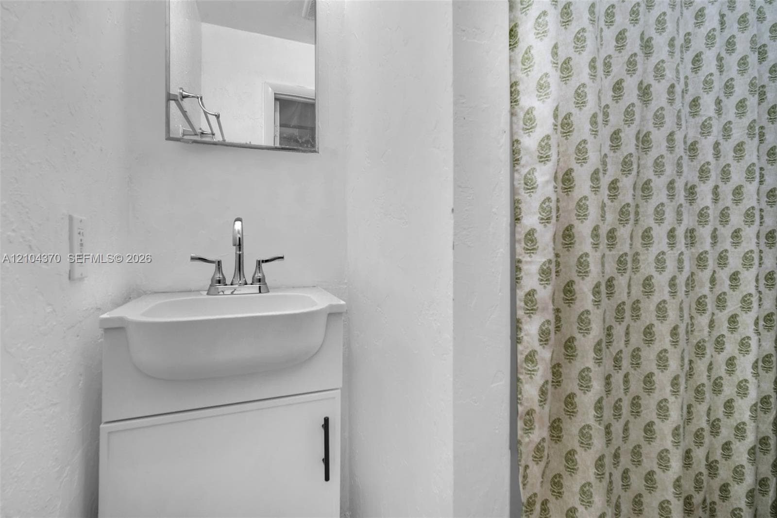 Room featuring neutral tile flooring, a wall-mounted mini-split climate control unit, and a ceiling fan with integrated lighting