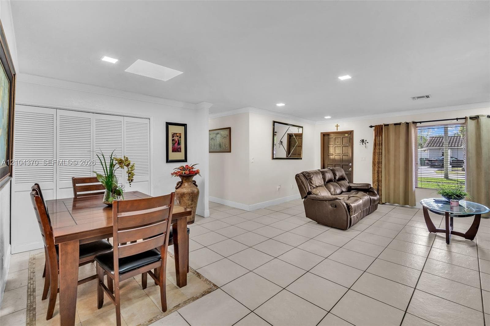 Living space featuring light-toned floor tile, crown molding, and recessed lighting