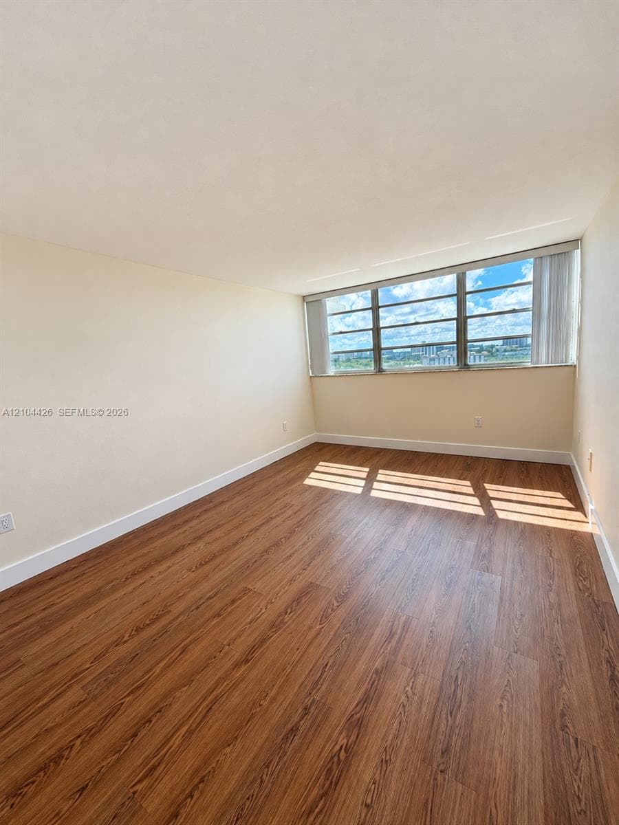Neutral-toned interior space featuring wood-finish flooring and a multi-pane window with a horizontal orientation