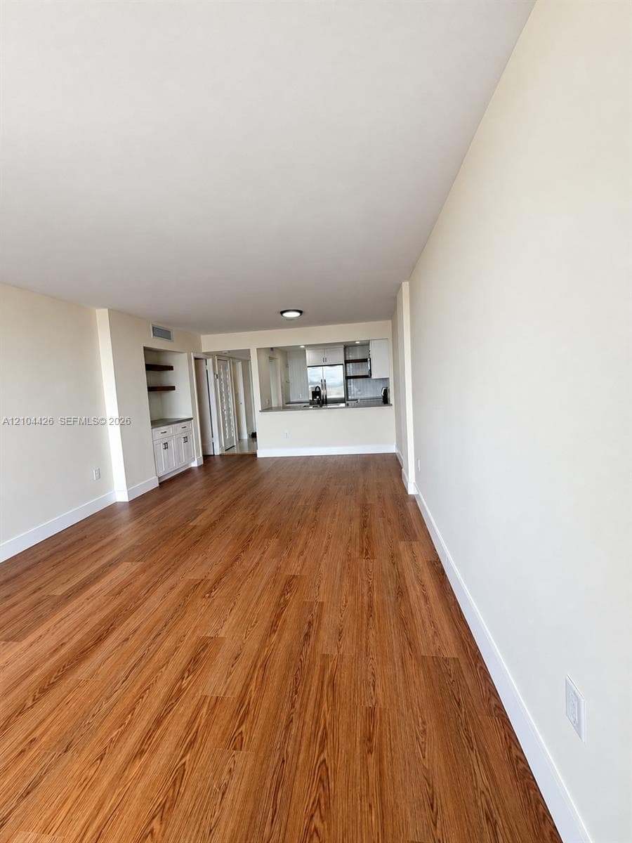 Wood-finish flooring, built-in cabinetry with shelving, pass-through opening, and recessed ceiling lighting