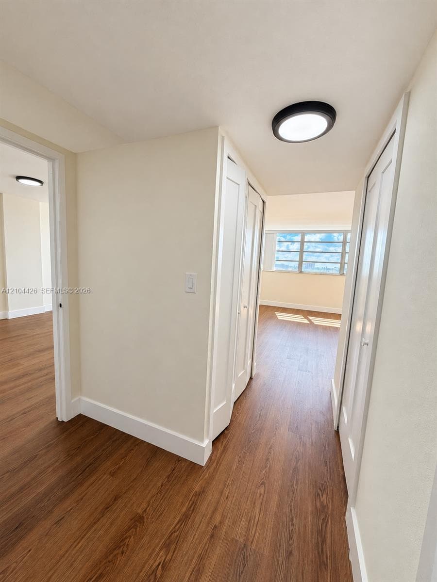 Wood-finish flooring, multi-panel closet doors, and flush-mount circular lighting fixtures