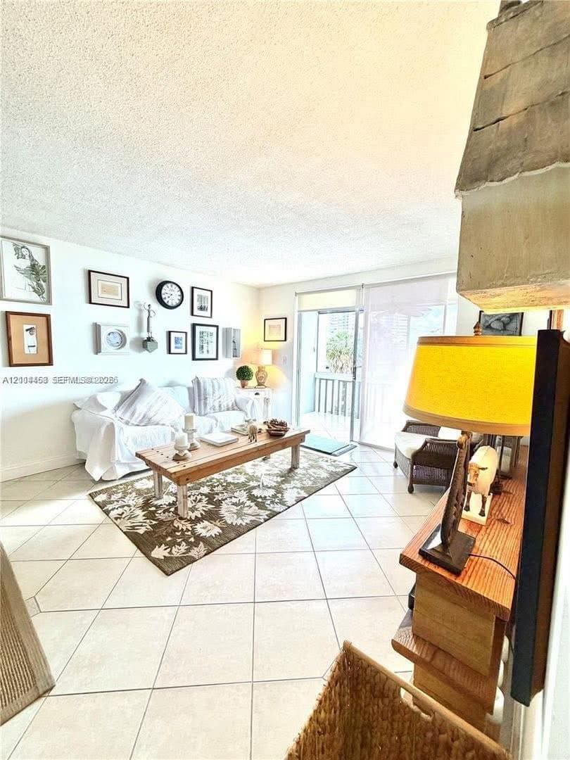 Living space featuring light-colored diagonal floor tile and sliding glass doors with balcony access