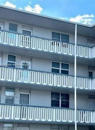 Multi-level exterior featuring white railings, grid-pattern windows, and gray siding