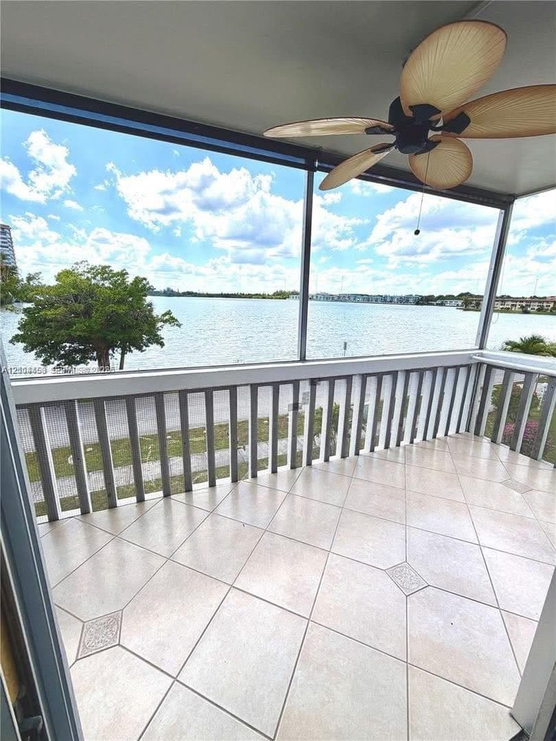 Screened balcony featuring tile flooring with decorative inserts, white railing, and a ceiling-mounted fan