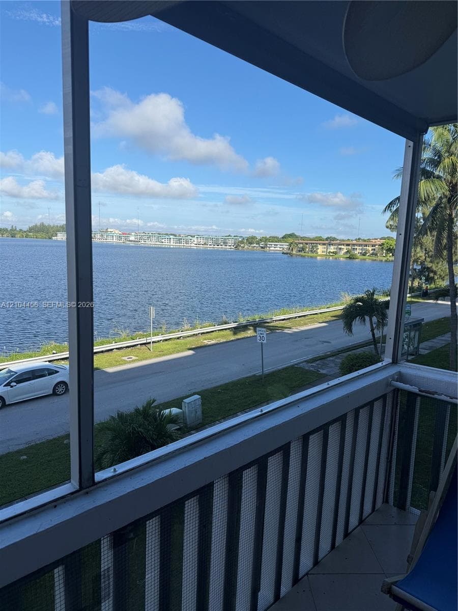 Screened balcony featuring tile flooring and metal railings, overlooking a large body of water