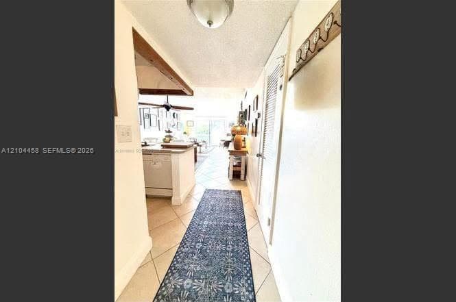 Interior hallway featuring diagonal ceramic tile flooring, a semi-flush mount ceiling fixture, and a louvered closet door