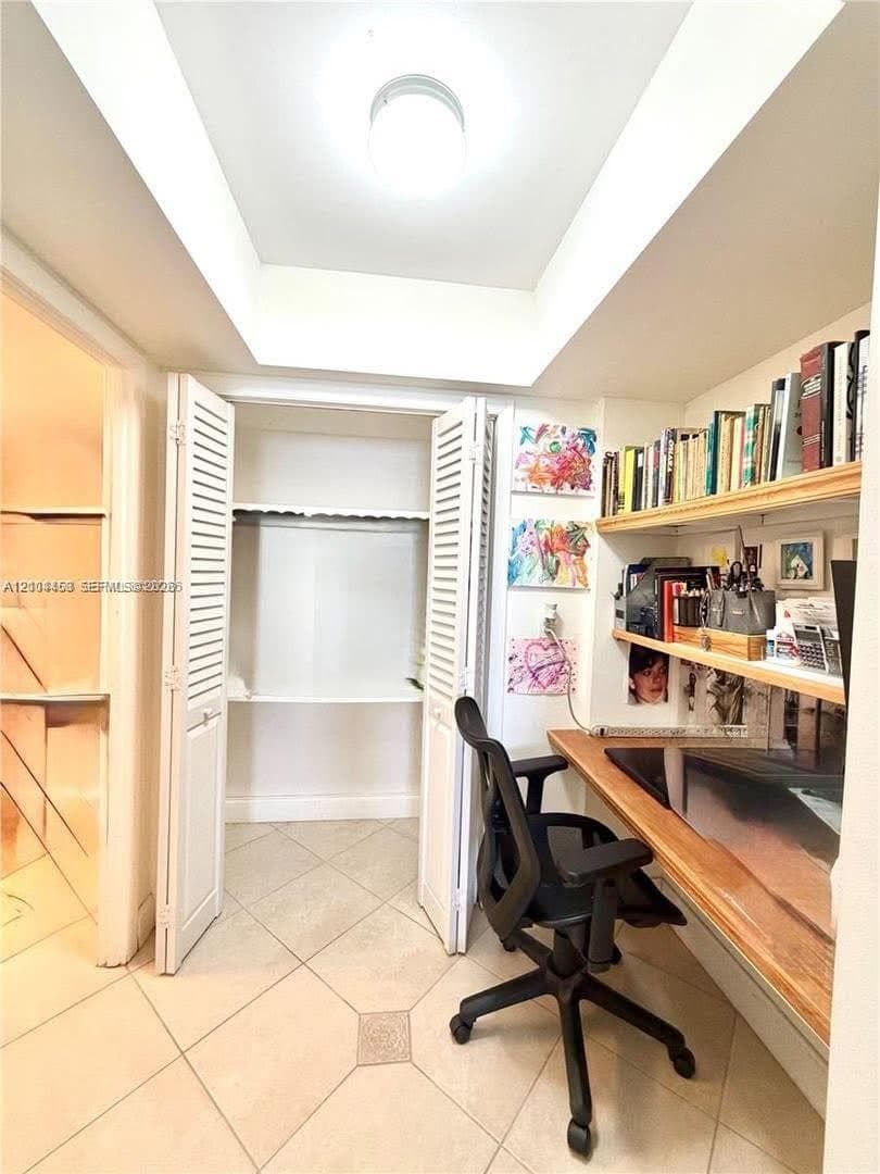 Built-in wooden desk, integrated wall shelving, ceiling tray feature, and louvered closet doors with interior shelving