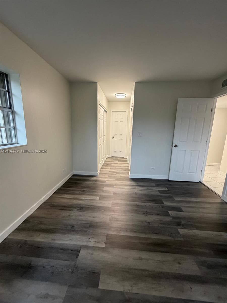 Wood-finish flooring, neutral wall tones, multi-panel interior doors, and a ceiling-mounted flush light fixture