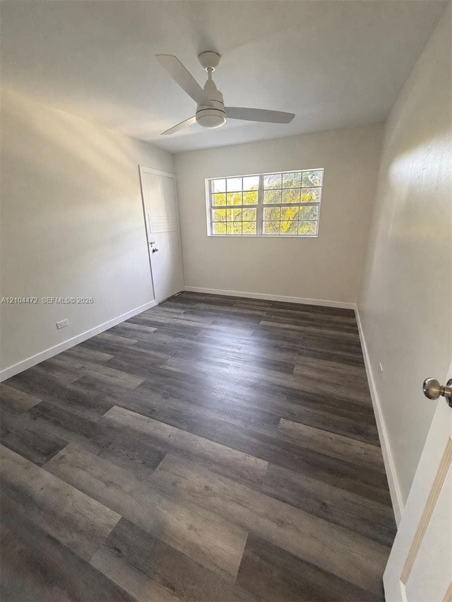 Neutral-toned interior featuring wood-finish flooring, a multi-pane window, and a ceiling-mounted fan