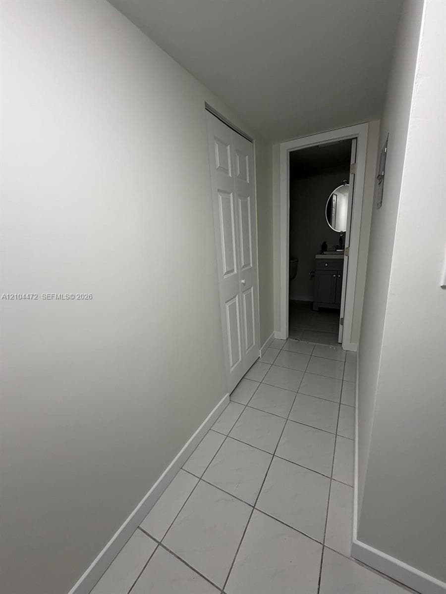 Hallway featuring light-toned ceramic tile flooring and a white paneled bifold closet door