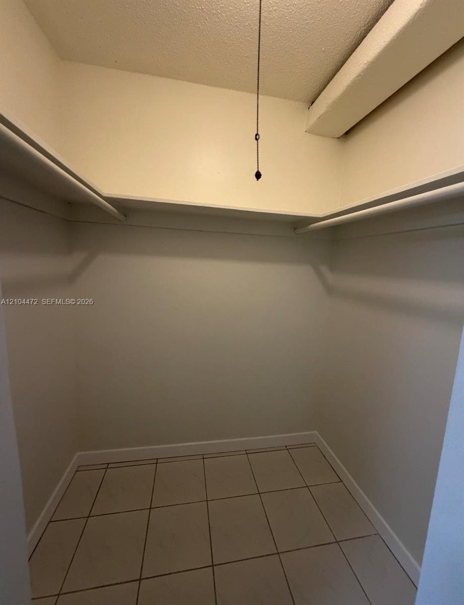 Walk-in closet featuring ceramic tile flooring, built-in shelving, and integrated garment rods
