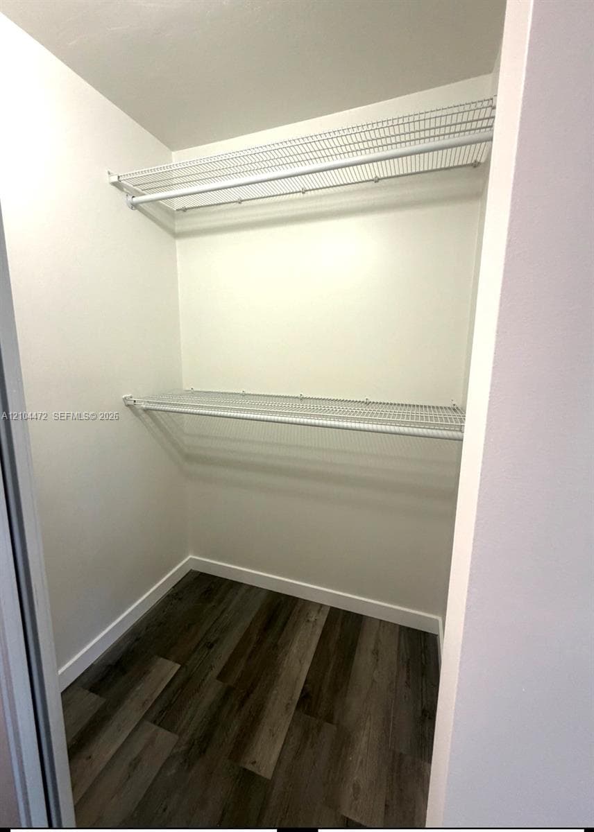 Storage closet featuring wood-finish flooring and dual tiers of white wire shelving