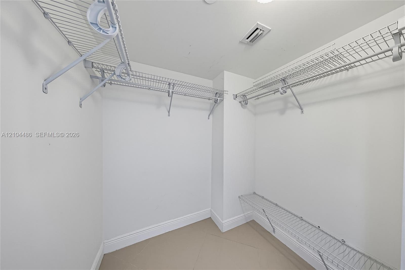 Walk-in closet featuring multi-level white wire shelving and tile flooring