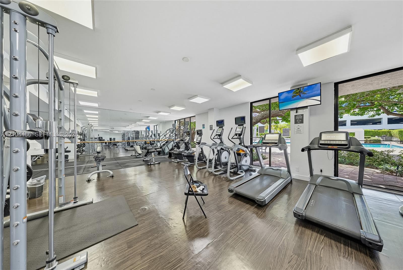 Fitness center featuring wood-finish flooring, floor-to-ceiling mirrored walls, and expansive windows
