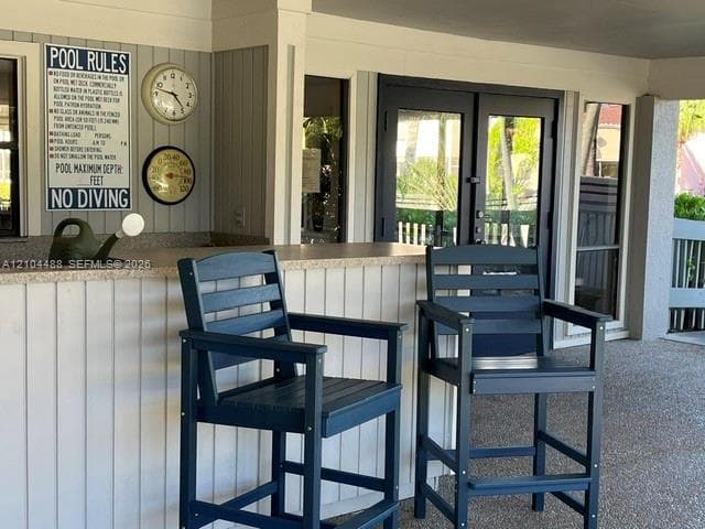Covered patio featuring a built-in stone-top service counter and double glass-paneled entry doors