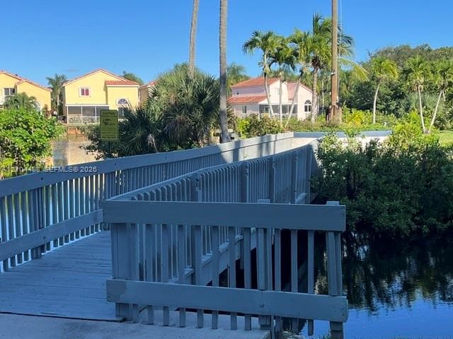 Pedestrian bridge with wooden decking and vertical railings spanning a waterway