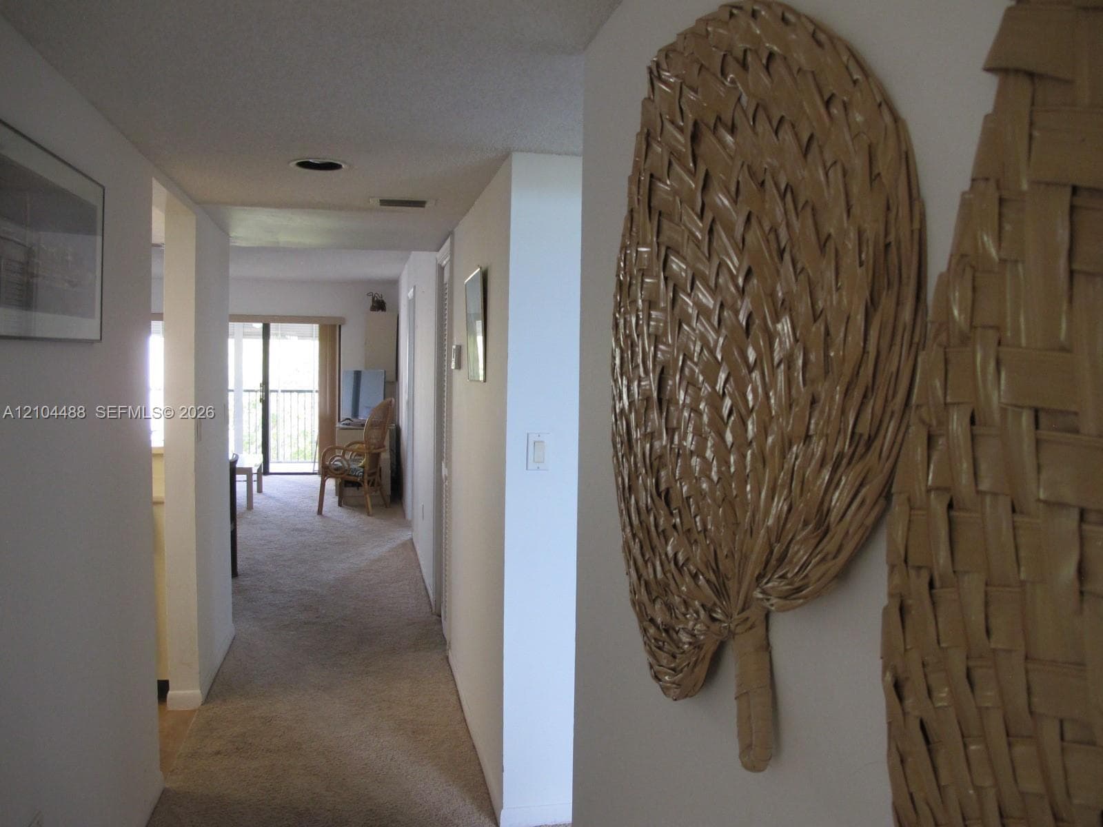 Carpeted hallway leading to a room with a sliding glass door and an exterior balcony