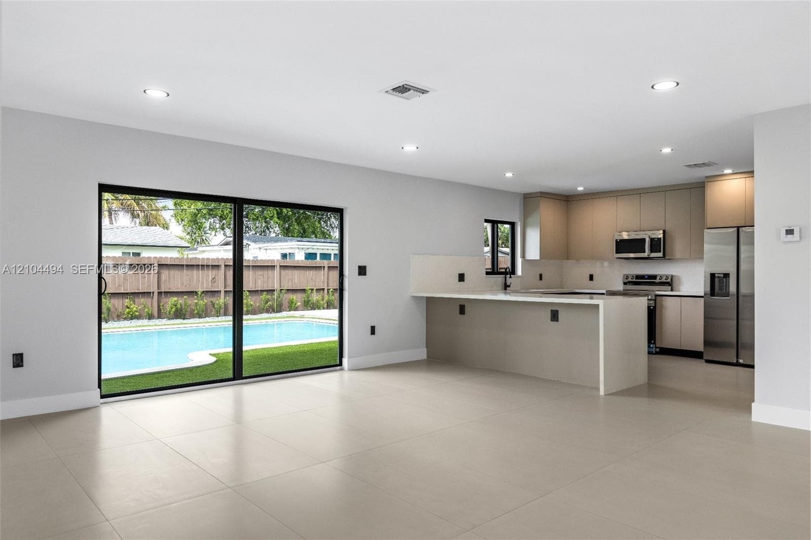 Open-concept interior featuring large-format tile flooring, recessed lighting, and sliding glass doors