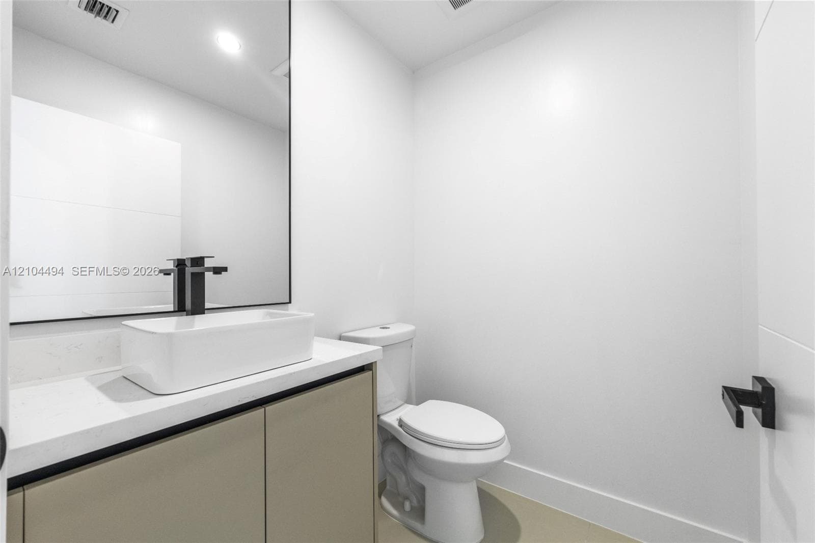 Vanity featuring a rectangular vessel sink, quartz countertop, matte black faucet, and frameless mirror, paired with a two-piece toilet and matching matte black hardware