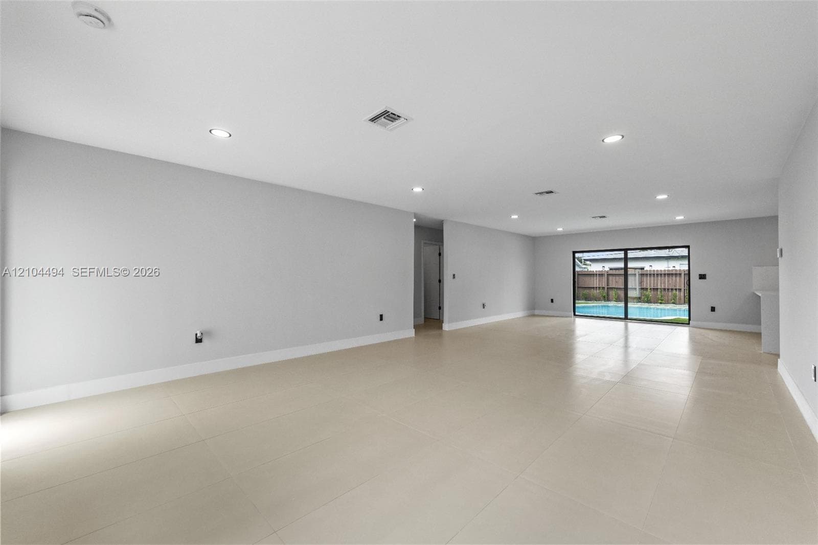 Open-concept interior featuring large-format tile flooring, recessed lighting, and expansive glass sliding doors