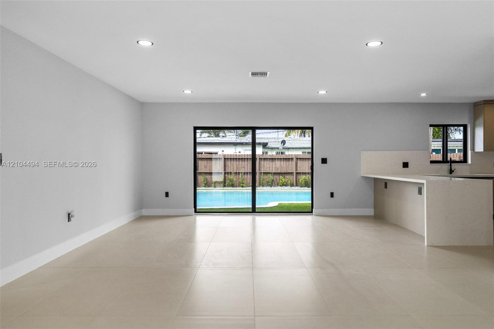 Open-concept interior featuring large-format tile flooring, recessed lighting, and a kitchen island with a quartz countertop