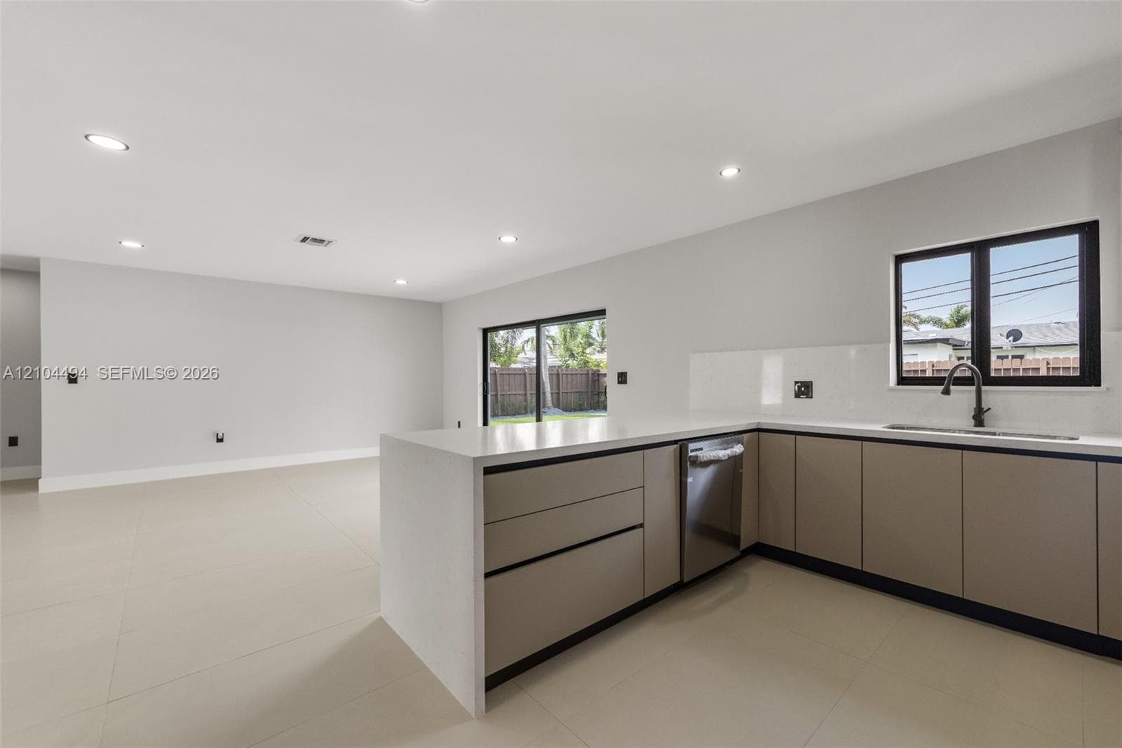 Kitchen featuring flat-panel cabinetry, light-toned stone-finish countertops, recessed ceiling lighting, large-format tile flooring, and matte black plumbing fixtures