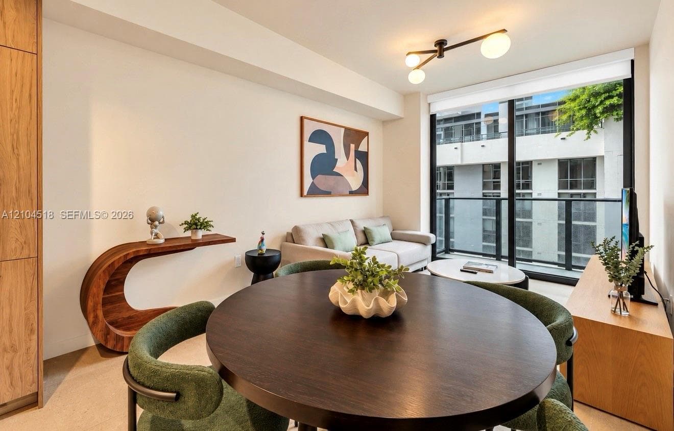 Open-concept living area featuring wood-finish flooring, a full-height glass door to the exterior, and a contemporary ceiling fixture
