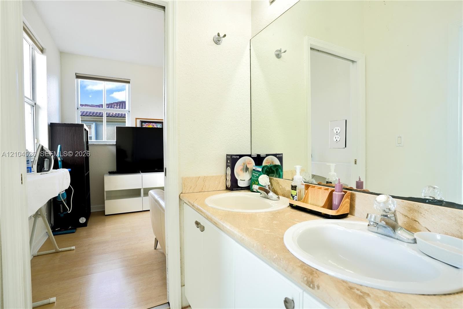 Dual-basin vanity featuring stone-finish countertops, undermount sinks, polished metal faucets, and a large wall-mounted mirror