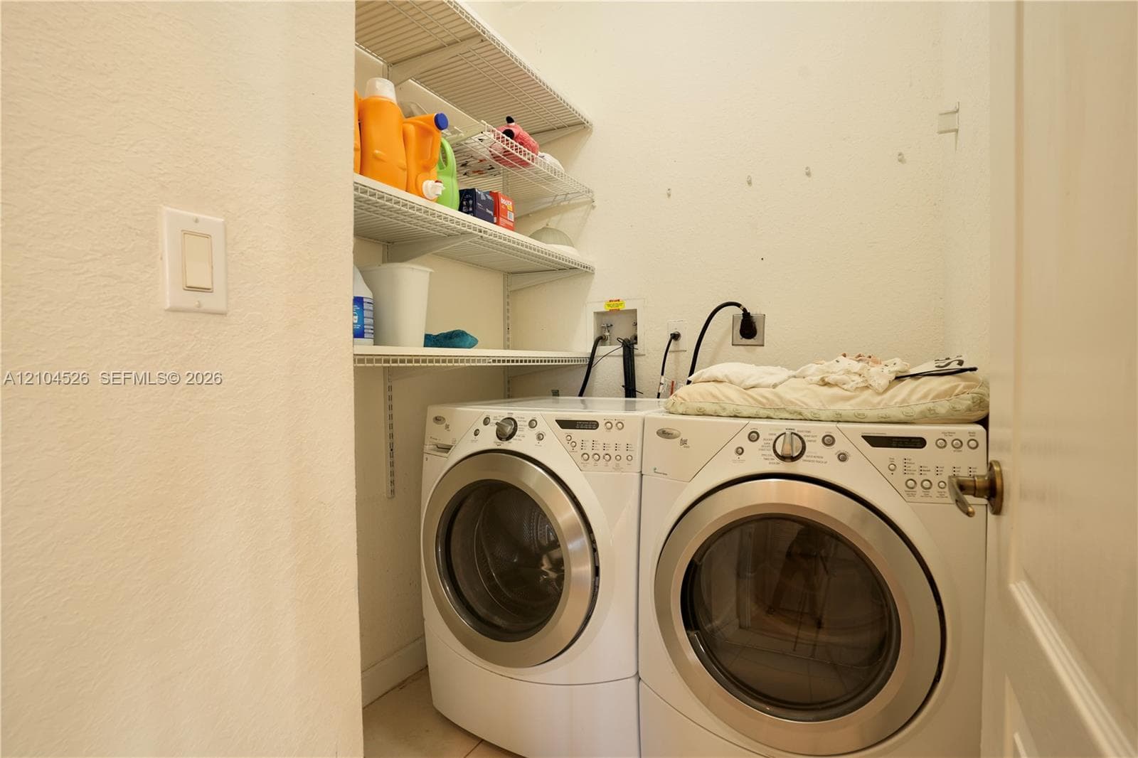 Utility area featuring white front-load laundry appliances and installed metal wire shelving