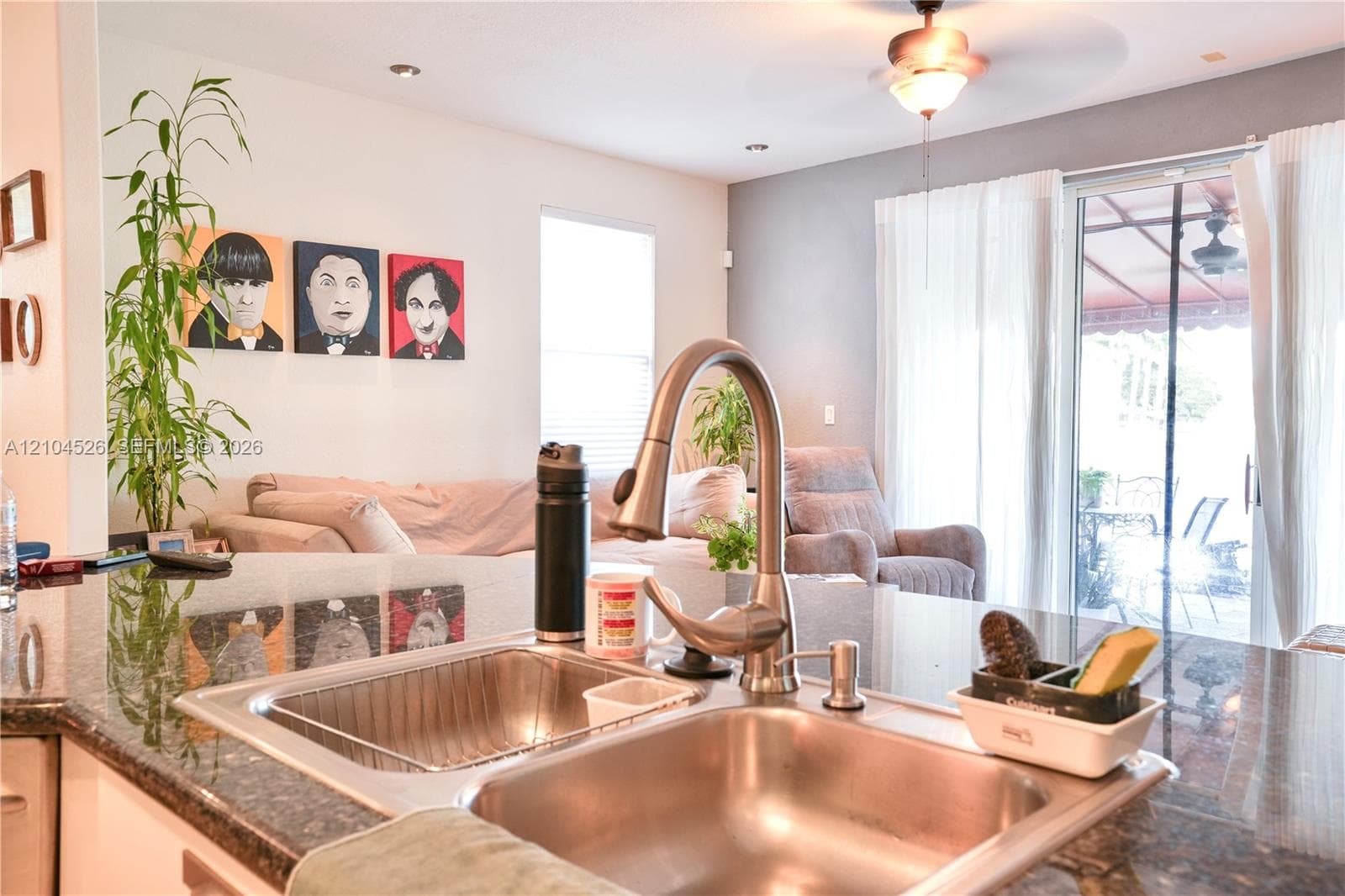 Kitchen island featuring a stone countertop, dual-basin stainless steel undermount sink, and a high-arch pull-down faucet