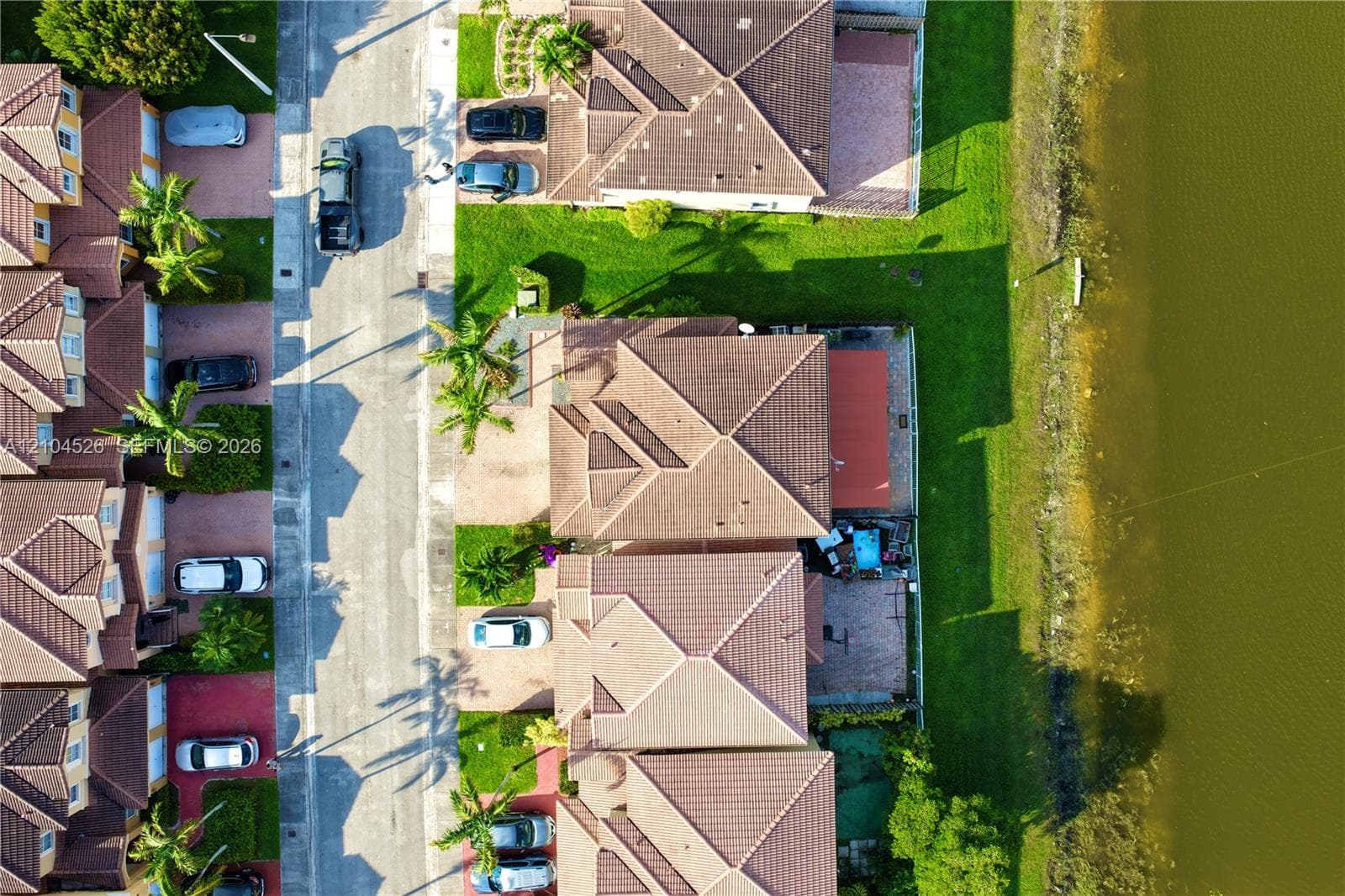 Aerial perspective of property featuring a concrete tile roof, paver driveway, rear paved patio, and water frontage