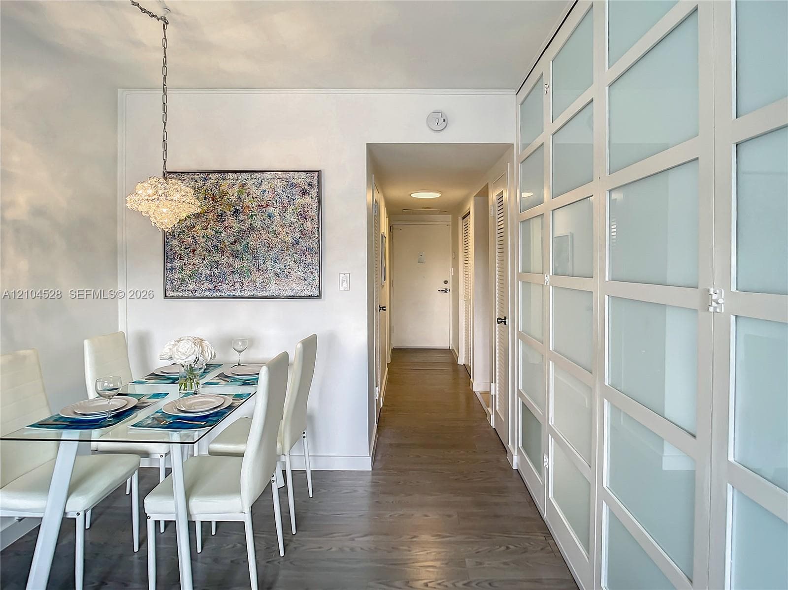 Full-height built-in cabinetry featuring frosted glass panel doors, wood-finish flooring, and a decorative hanging pendant light fixture