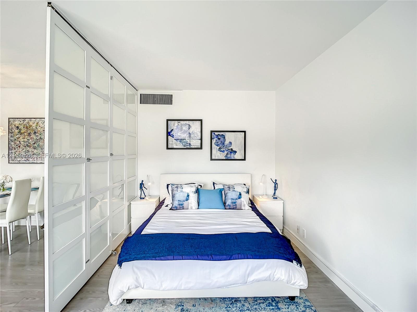 Floor-to-ceiling glass panel room divider with white frames and light-tone wood-finish flooring