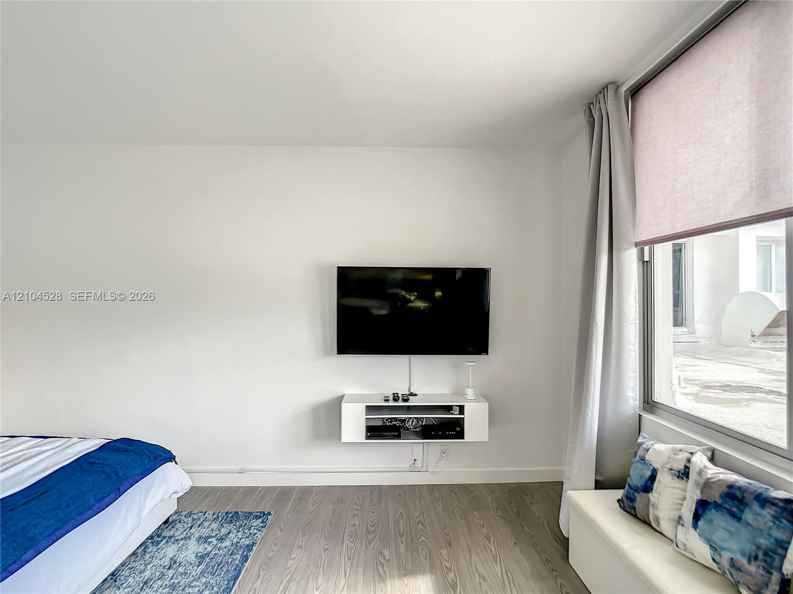 Wood-finish flooring, wall-mounted floating cabinet, and expansive window with integrated roller shade