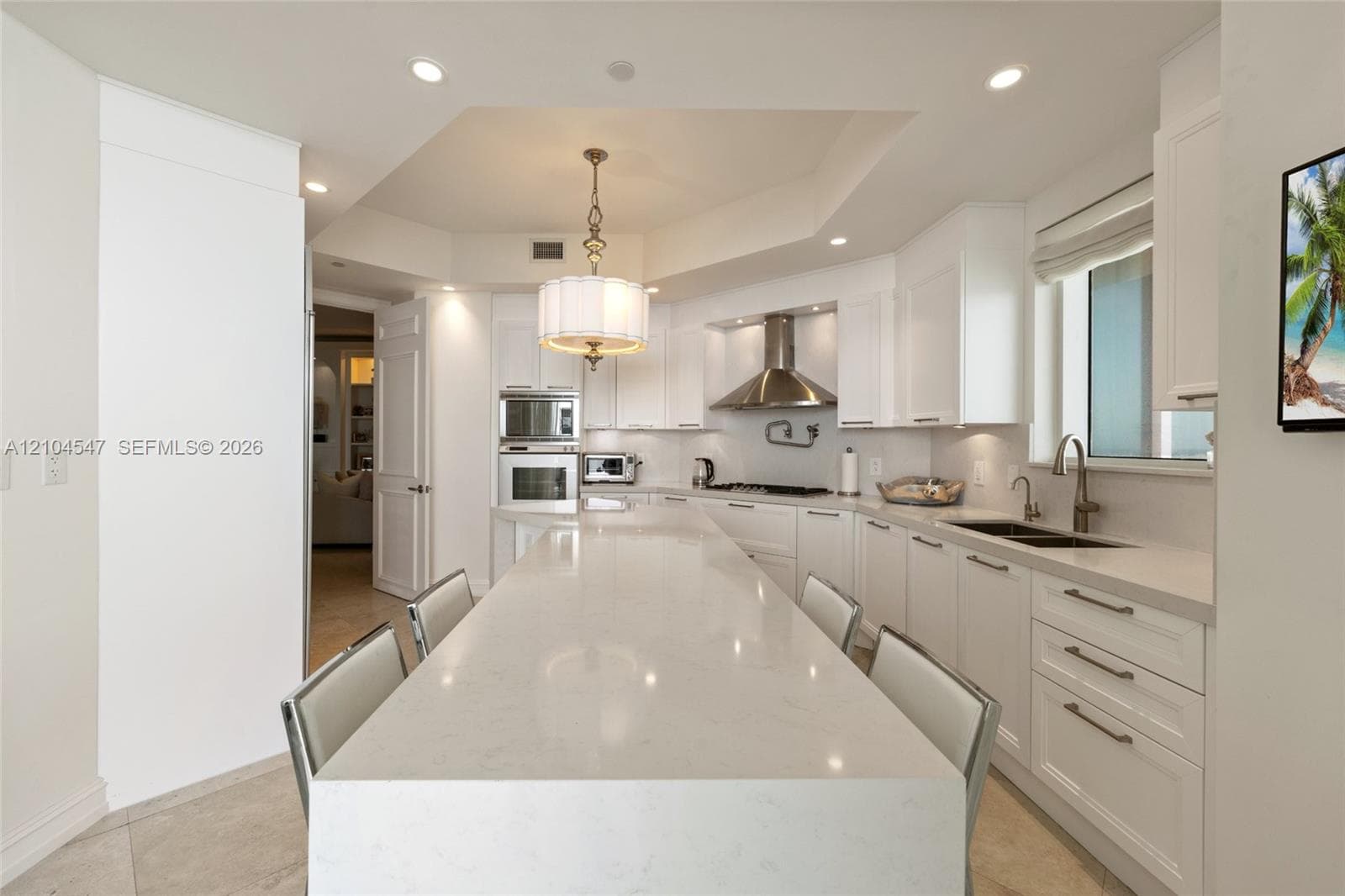 Kitchen featuring white shaker-style cabinetry, a large central quartz island, built-in stainless steel double ovens, a stainless steel range hood, and recessed lighting