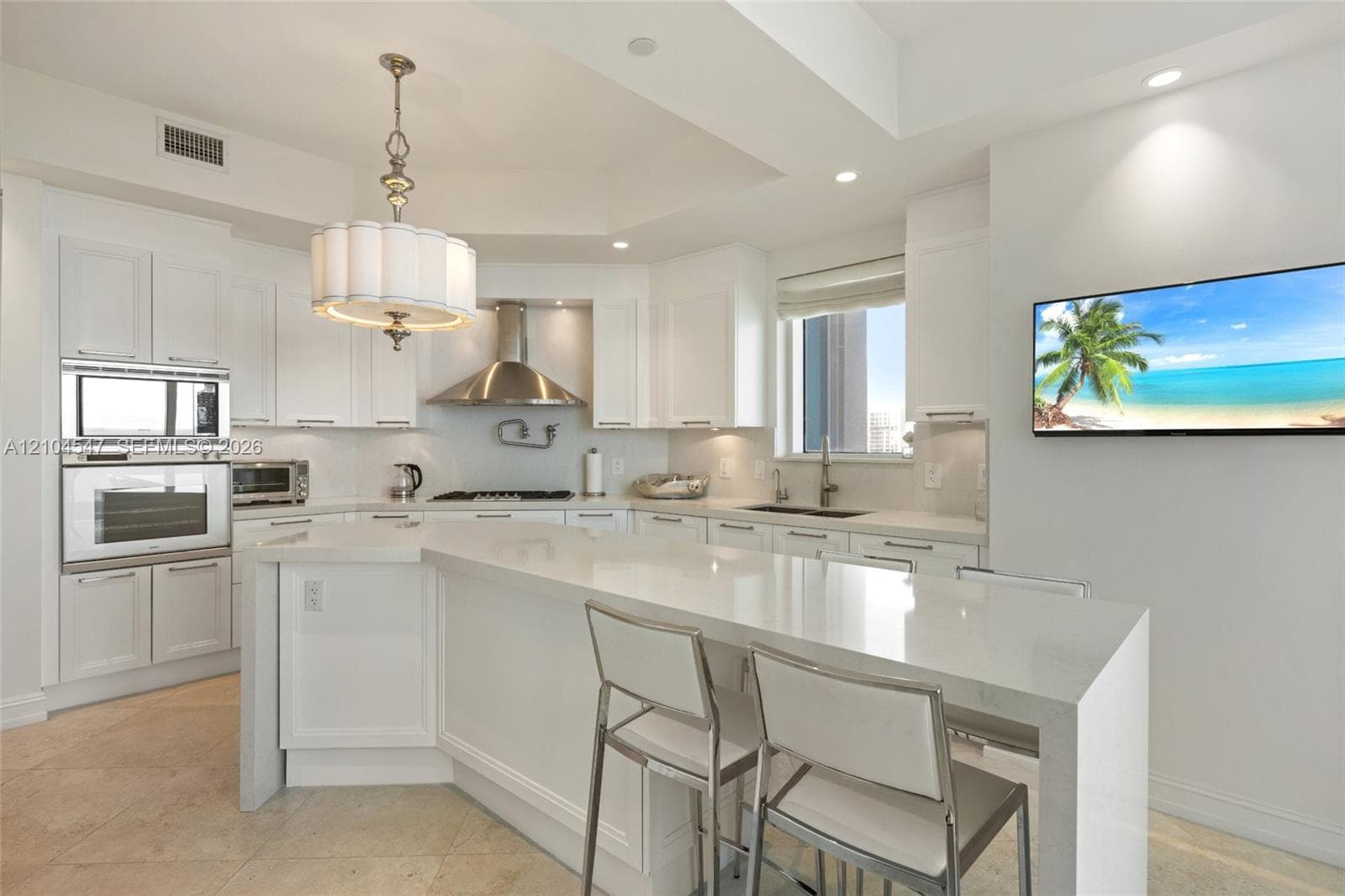 Kitchen featuring white cabinetry, an expansive waterfall-edge stone island, stainless steel wall-mounted oven and microwave, professional-grade range hood, and recessed lighting