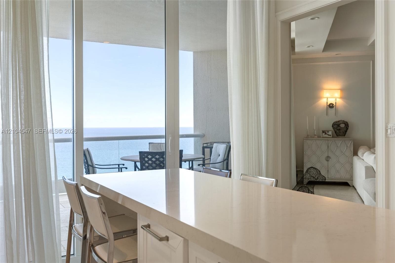 Quartz countertop island, floor-to-ceiling glass sliding doors, and private balcony with glass railing