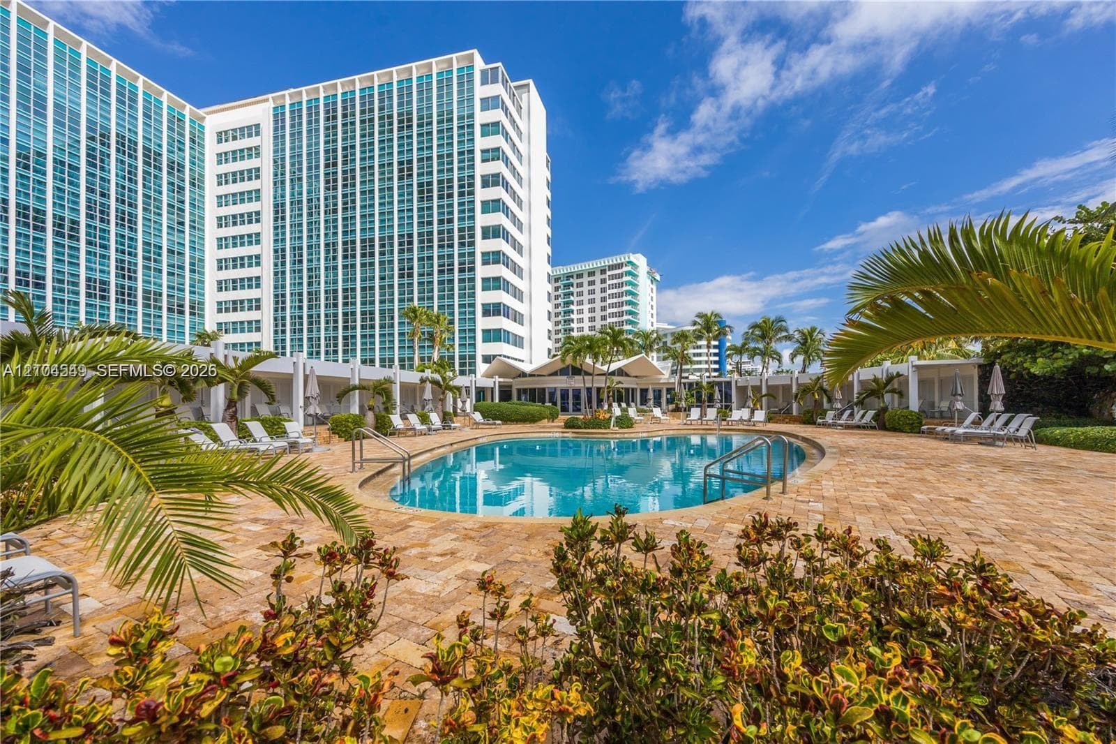Resort-style pool area with a curvilinear swimming pool, paver deck, and multiple cabanas
