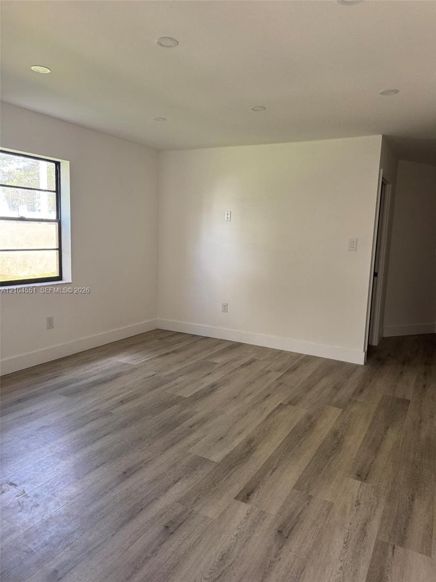Interior space featuring wood-finish flooring, recessed lighting, and a single-pane window with black framing