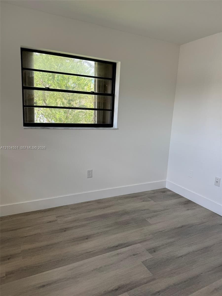 Neutral interior featuring wood-finish flooring, crisp white walls, and a multi-pane horizontal window with a stone-finish sill