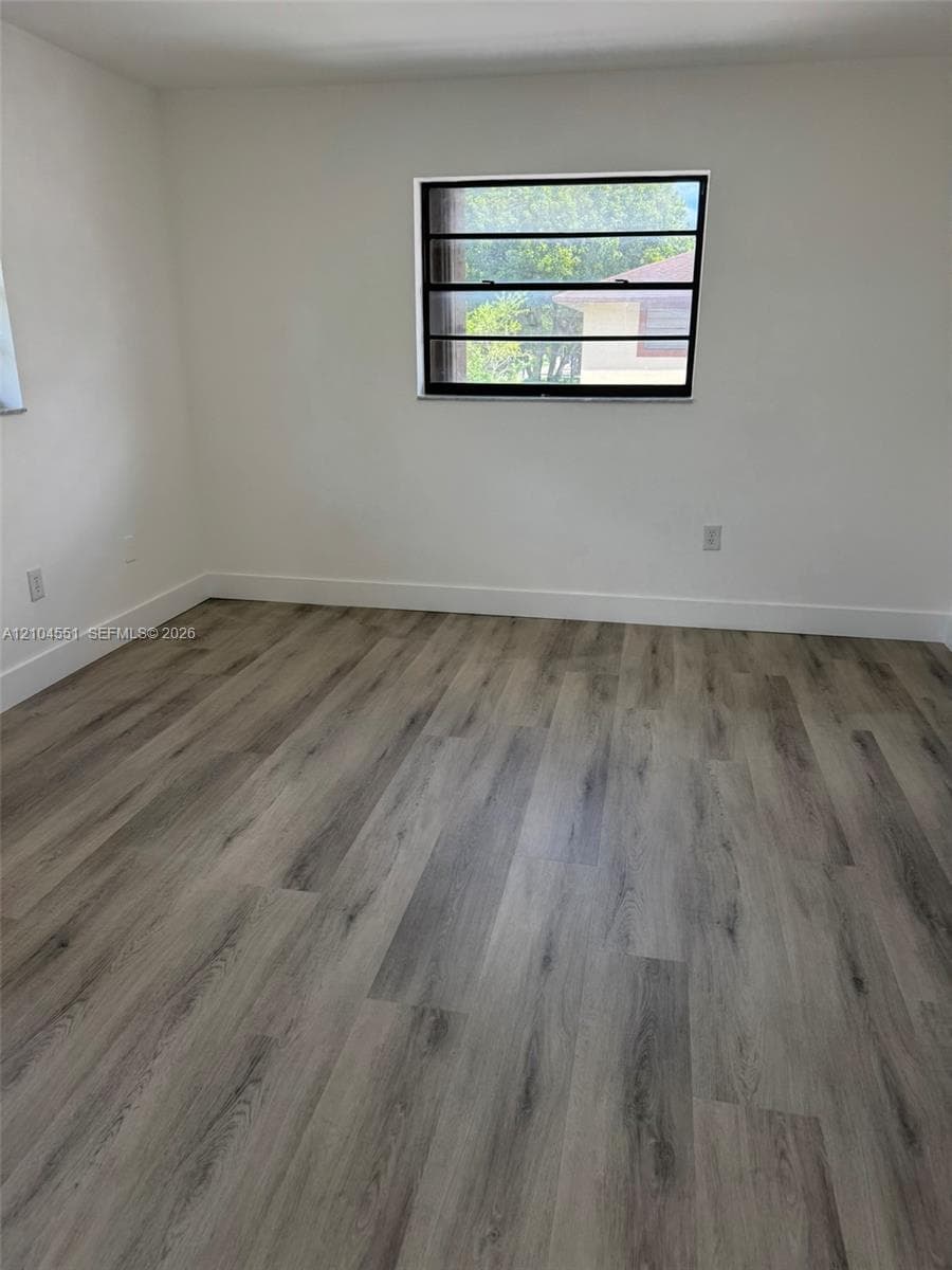 Neutral-toned interior space featuring wood-finish flooring and a multi-pane jalousie window