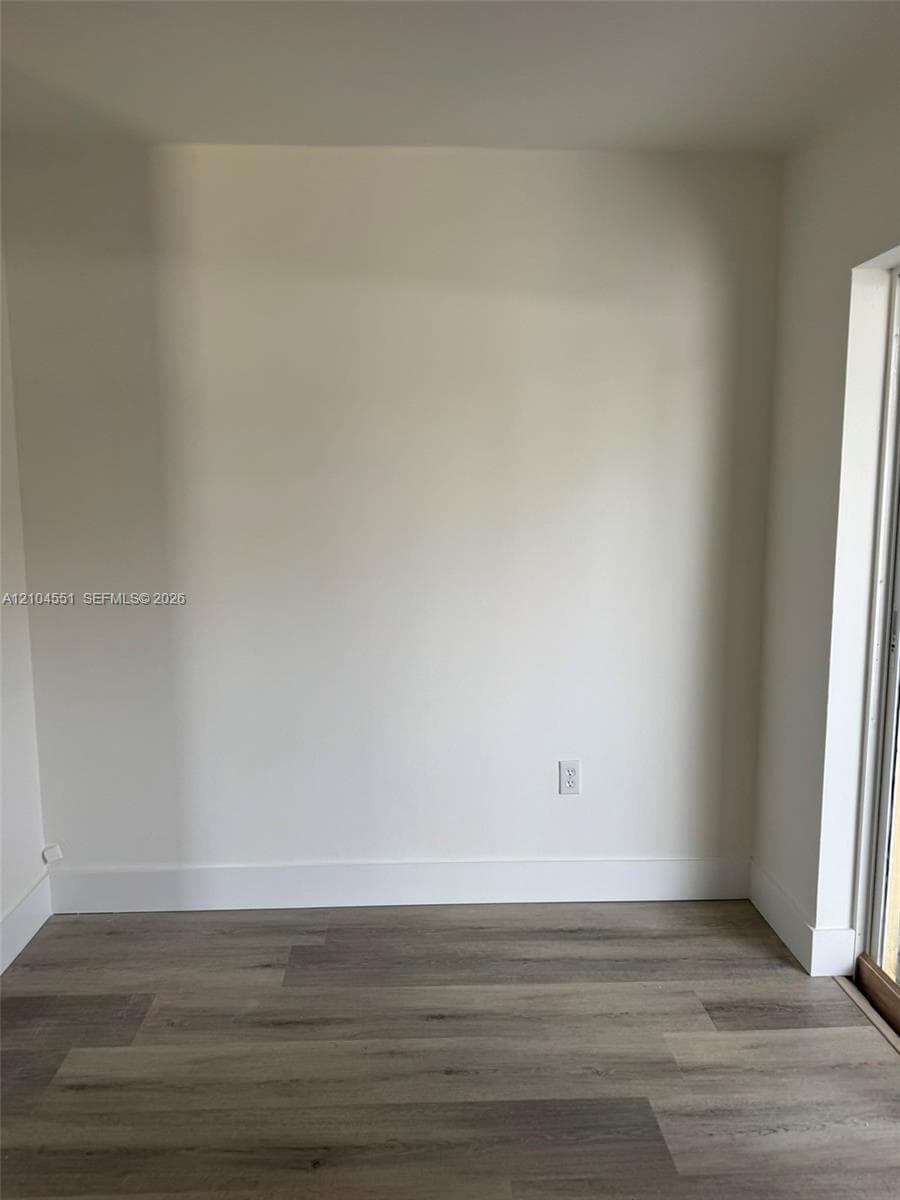 Neutral interior space featuring wood-finish flooring and light-toned wall surfaces