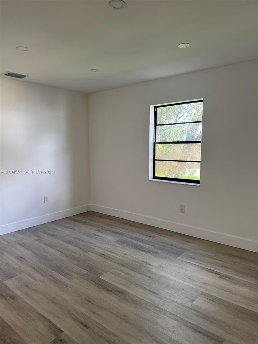 Neutral-toned walls, wood-finish flooring, and a single-hung window with dark-toned framing