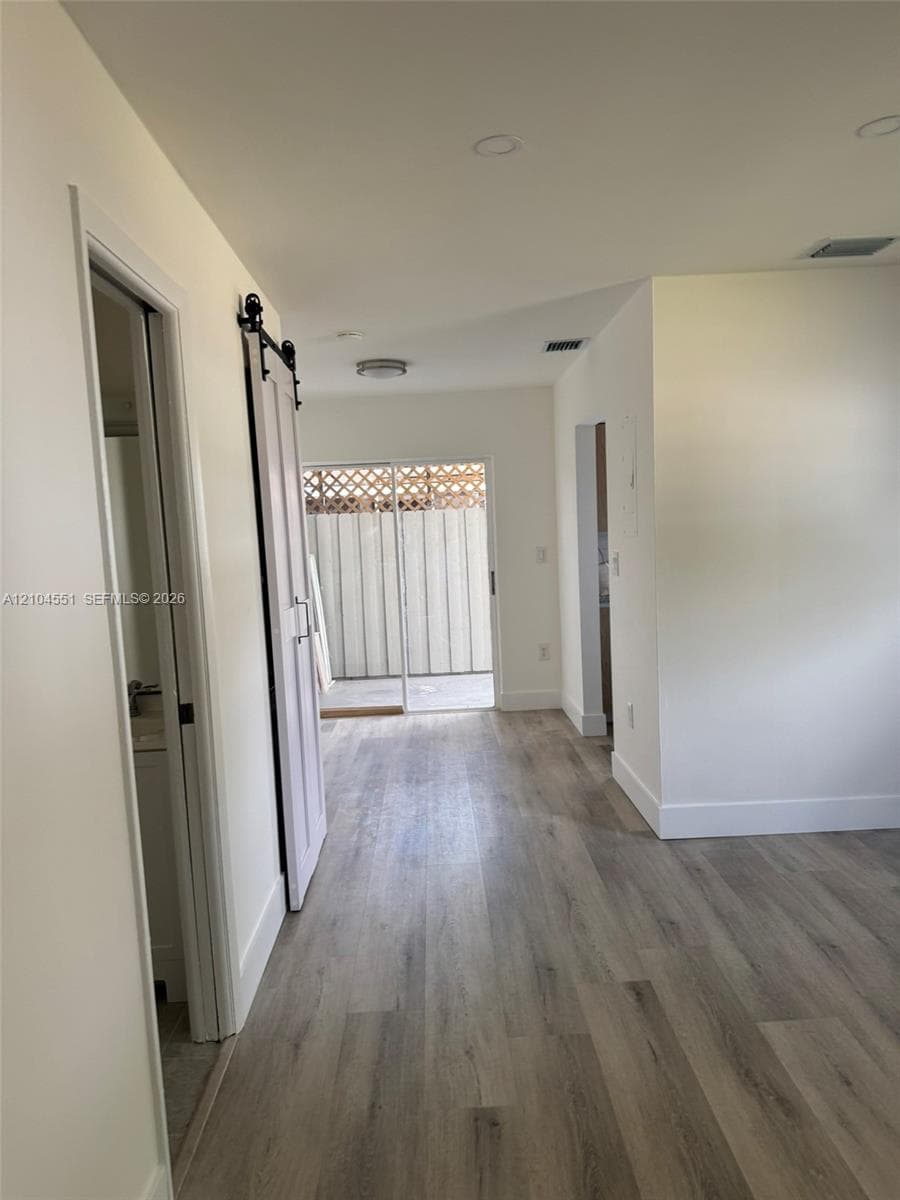 Interior space featuring wood-finish flooring, sliding barn door, recessed lighting, and a sliding glass door providing external access